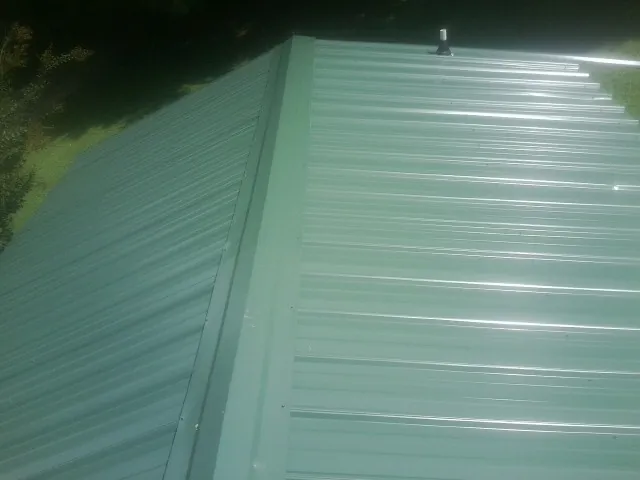 New green metal panels meeting at the ridge of a roof — Flat Roof Repair work by our crew in Crab Orchard