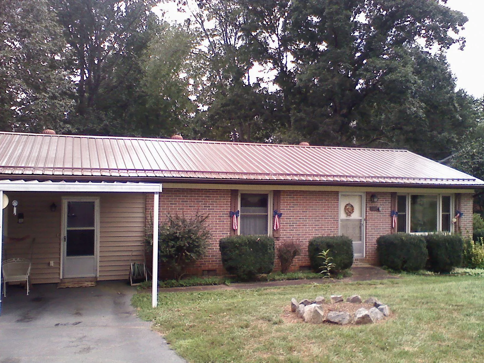 Bronze metal roof and carport on a brick ranch home — Roof Repair work by our crew in Crab Orchard